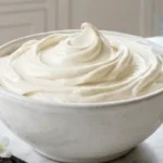 Best Vanilla Buttercream Frosting in a white bowl on a marble countertop.