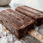 Two-Ingredient Fudge Pops served on crushed ice in a white marble kitchen
