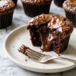Brownie cupcakes with crackly tops on a white marble counter