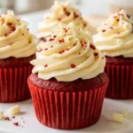 Red velvet cupcakes with cream cheese frosting on white marble countertop