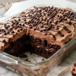 Ultimate Chocolate Poke Cake with whipped chocolate frosting in a glass baking dish
