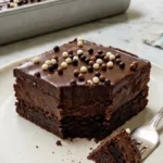 Chocolate Fudge Crunch Tray Bar with glossy ganache and chocolate pearls on a white plate.