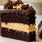 Chocolate Peanut Butter Cream Layer Cake with thick peanut butter filling, chocolate ganache, roasted peanuts, and chocolate curls.
