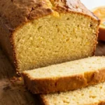 Orange bread in blender with fresh orange on a white marble countertop