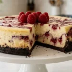 Raspberry swirl chocolate crust cheesecake with a sliced piece showing raspberry ribbons