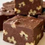 Old-Fashioned Chocolate Nut Fudge squares with walnuts on a white plate