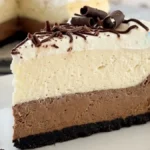 Triple Chocolate Vanilla Mousse Cheesecake with chocolate crust, vanilla mousse, whipped cream and chocolate curls