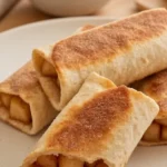 Cinnamon sugar apple pie roll-ups with diced apple filling on a speckled plate